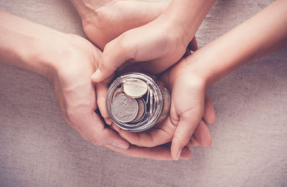 hand holding jar filled with coins