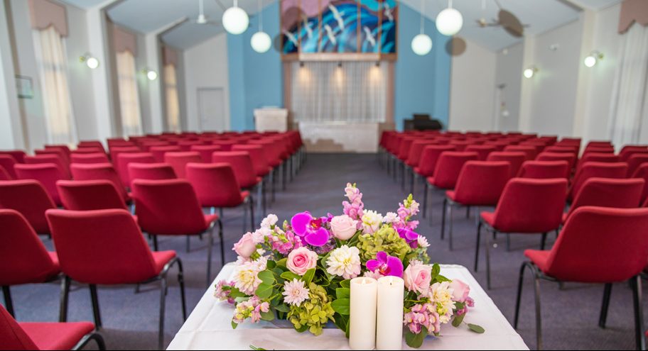 Chapel with sitting area and candles kept near funeral flower bouquet